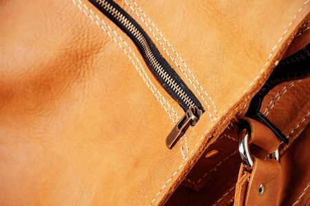 Zipper on a brown leather bag with texture of details.