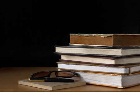 Old book stack on wooden table with black background.の写真素材