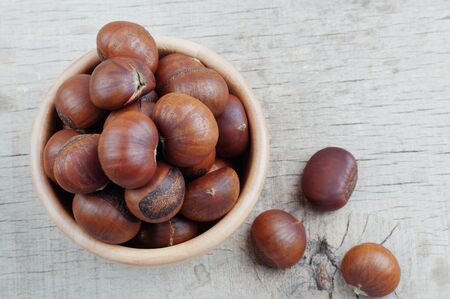 Chestnuts roasted in a bowl on wooden floor.の写真素材