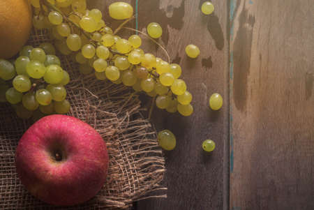Red apples and grapes on old wooden floor.の写真素材
