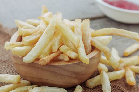 French fries in bowl and sauce on wooden table.