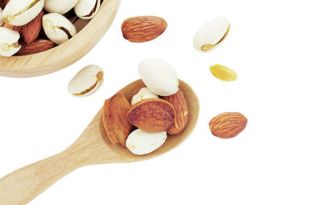 Almonds on wooden spoon and bowl with a white background.の写真素材