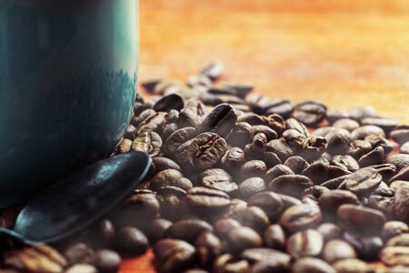 Roasted coffee beans and cups on wooden table.の写真素材
