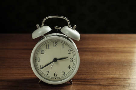 alarm clock on wooden with a black background.の写真素材