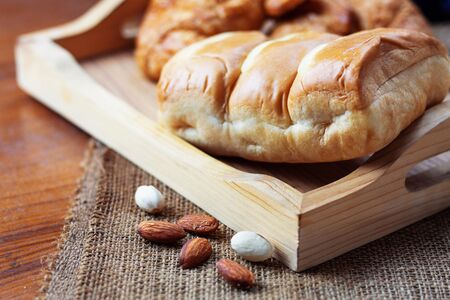 Bread on tray and almonds of wooden floor.の写真素材