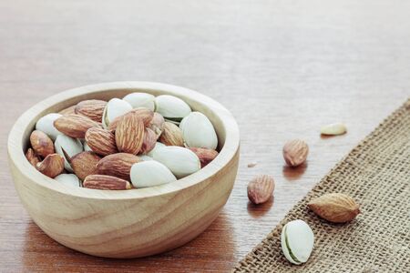 Almonds in the bowl and wooden floor.の写真素材