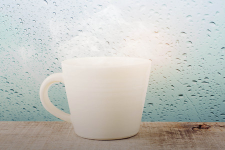 Coffee mug and droplets on glass in rainy season.の写真素材