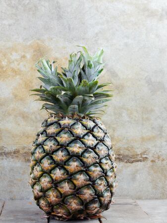 Pineapple on wooden floor with the old wall.の写真素材