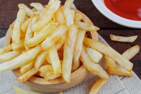 French fries on wooden bowl and sauce in saucerの写真素材