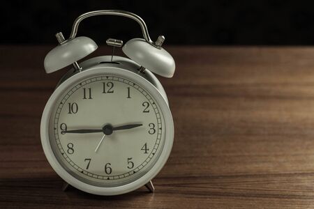 Alarm clock on wooden floor with a black background.の写真素材