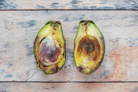 avocado is cut half and rotten on the old wooden floor.の写真素材