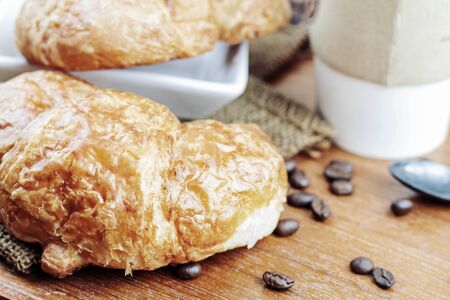 Croissants and coffee cup on a wooden floor.の写真素材