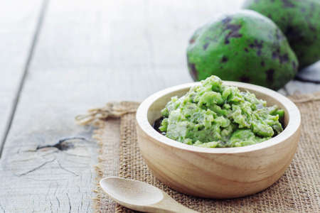 Grated avocado in bowl and green on wooden floor.の写真素材