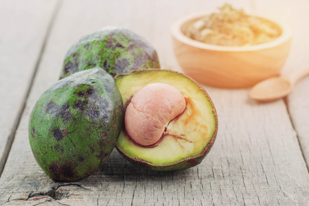 Half cut avocado and green peel on wooden floor.の写真素材
