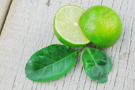 Fresh lime slices and leaves on wooden floor.の写真素材