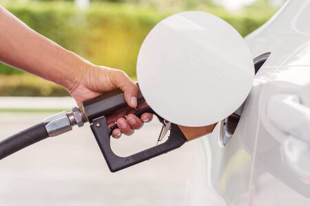 hand is holding the fuel tank at the gas station.の写真素材
