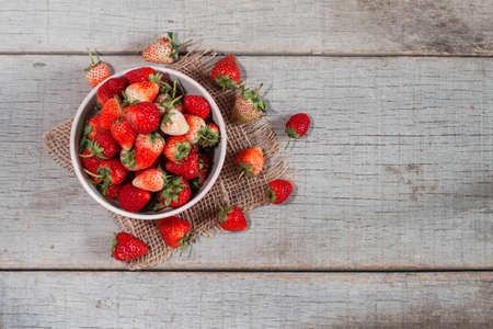 Strawberries in a bowl on the old wooden table.の写真素材