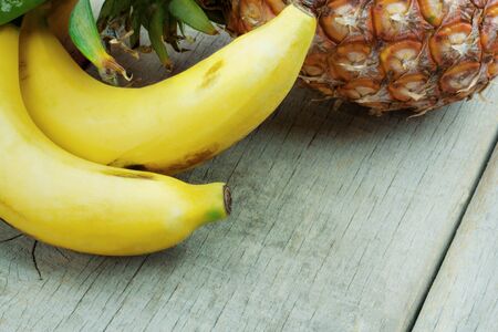 Banana and pineapple on the old wooden floor.の写真素材
