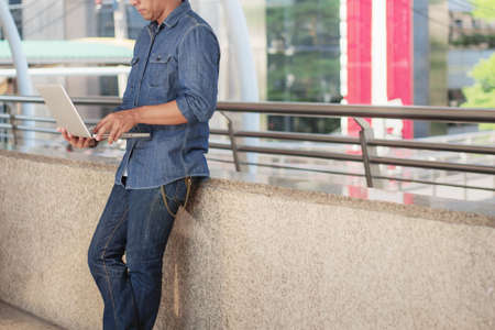 young man is standing using a computer in the city.