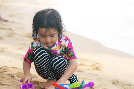 Asian girl playing toy on sand beach.の写真素材