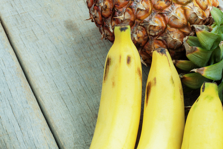 Banana ond pineapple on a wooden background.の写真素材