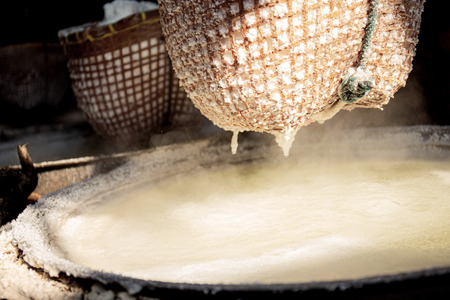 Hot pan on a clay stove with salt in a bamboo basket.の写真素材