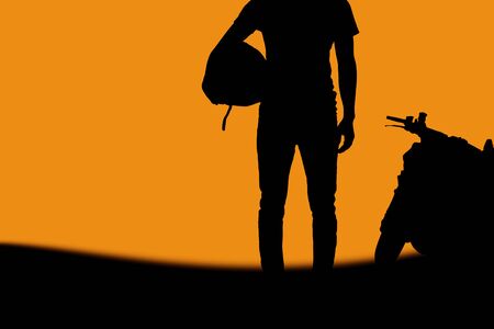 Man of biker in field with the silhouette at sky.の写真素材