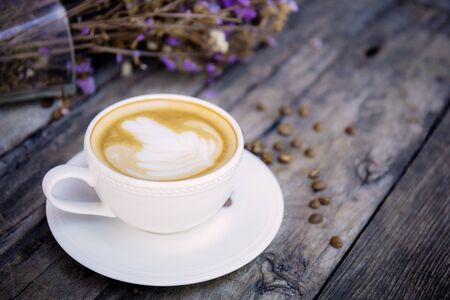 Coffee cup on wood and vaes flower background.の写真素材
