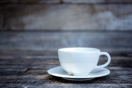 Coffee cup on wooden table at wall with background.