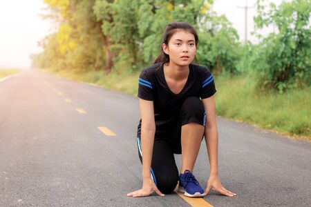 Girl is preparing to run on street in the park.の写真素材