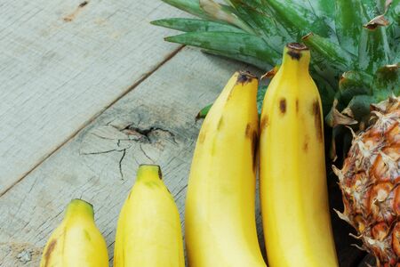 Banana ripe and pineapple on a wooden background.の写真素材