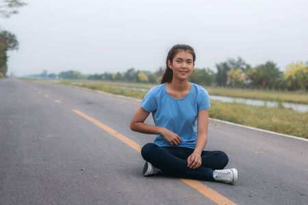 Girl is sitting on street in a park.の写真素材
