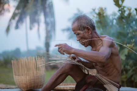 Old man are weaving basket in the countryside of Thailand.の写真素材