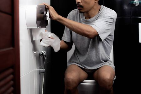 Hand of man using toilet paper at home.の写真素材