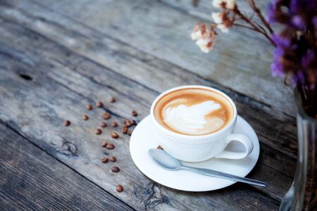 Coffee cup on wooden table and vase flower.の写真素材