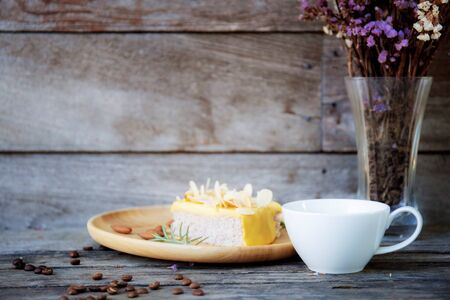 Coffee cup on wooden table and vase of flower at wall.の写真素材