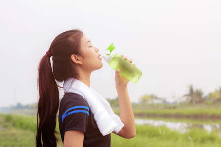 Asian girl drinking water after exercise in a park.の写真素材