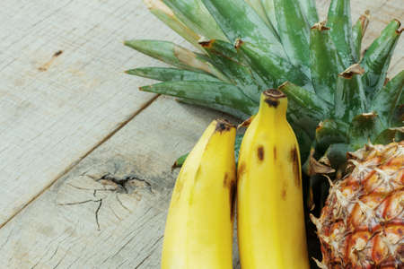 Banana ripe and pineapple on the old wooden.の写真素材