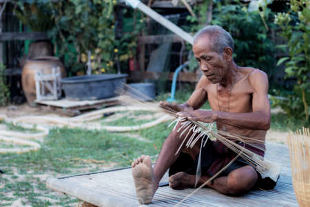 Old man are weaving in countryside of Thailand.の写真素材