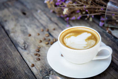 Coffee cup and vase with decoration on wooden table.の写真素材