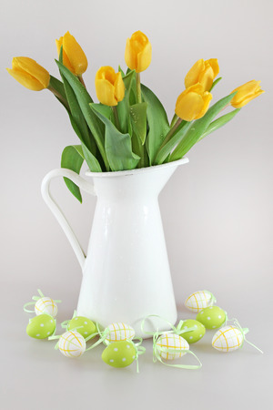 Bouquet of yellow tulips in jug and easter eggsの写真素材