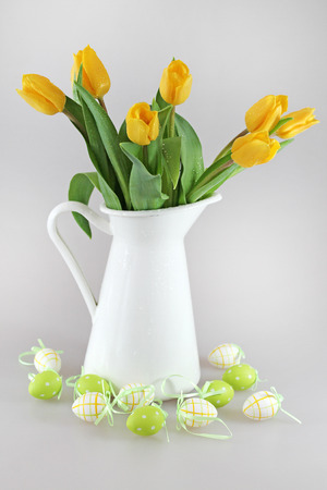 Bouquet of yellow tulips in jug and easter eggsの写真素材