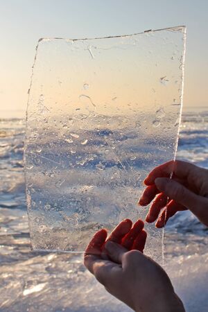 Ice background. Woman hands holding ice. Lake Balaton in Winter, Hungary.