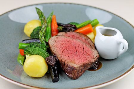 Beef steak with steamed vegetables at restaurant close up.の写真素材