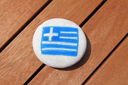 Greece country flag painted on the sea stone on wooden plank background.の写真素材