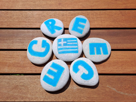 Greece country name painted on the stones on wooden plank background. Inscription on the sea stones.の写真素材