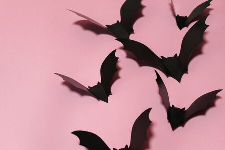 halloween, decoration and scary concept - black bats flying over lilac background