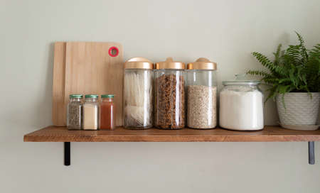 Zero waste storage in the kitchen. Various cereals, pasta, oatmeal, flour in reusable glass jars on the table on the wooden shelf. Eco friendly lifestyleの写真素材