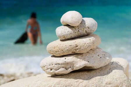 stacked pebbles on the beach, woman at blurred backgrondの写真素材