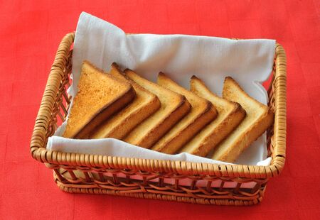 toasted triangle slices of bread in the wicker basket, red napkin background